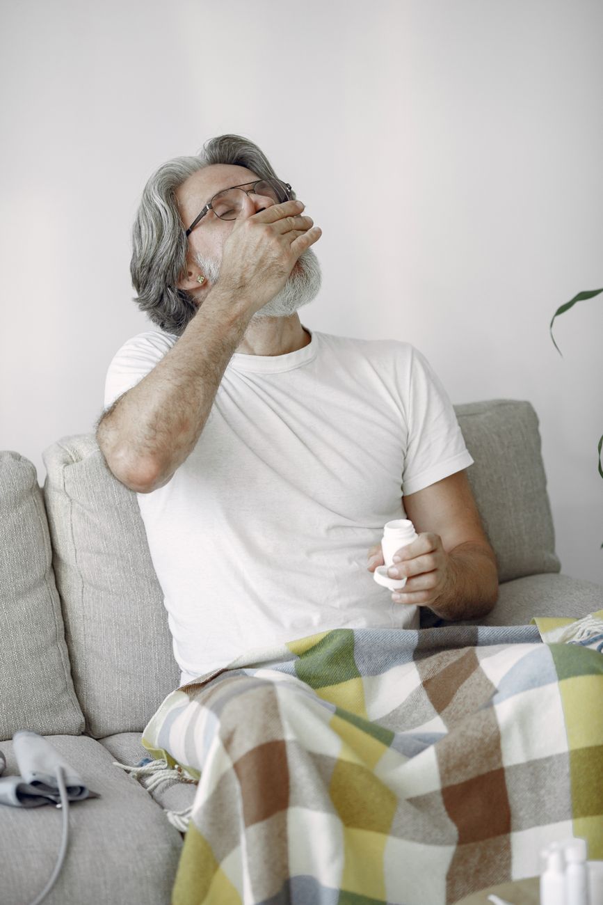man sitting on the couch drinking his medicine